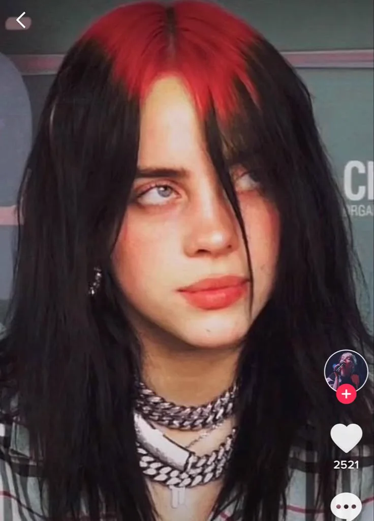 Billie Eilish with vivid red ghost roots through the crown and long black hair