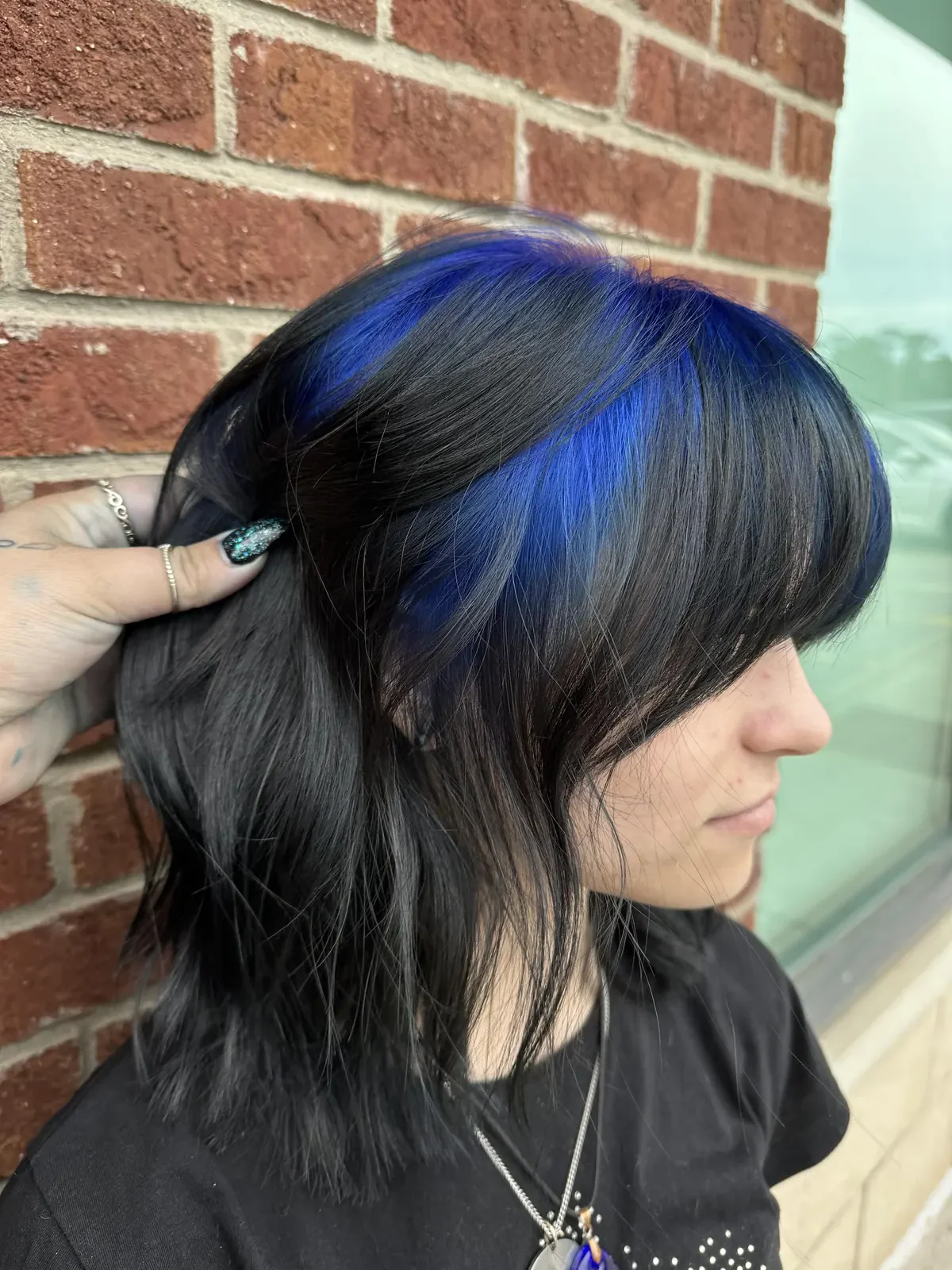 Black layered wolf cut with electric blue ghost roots and a visible blue side panel.