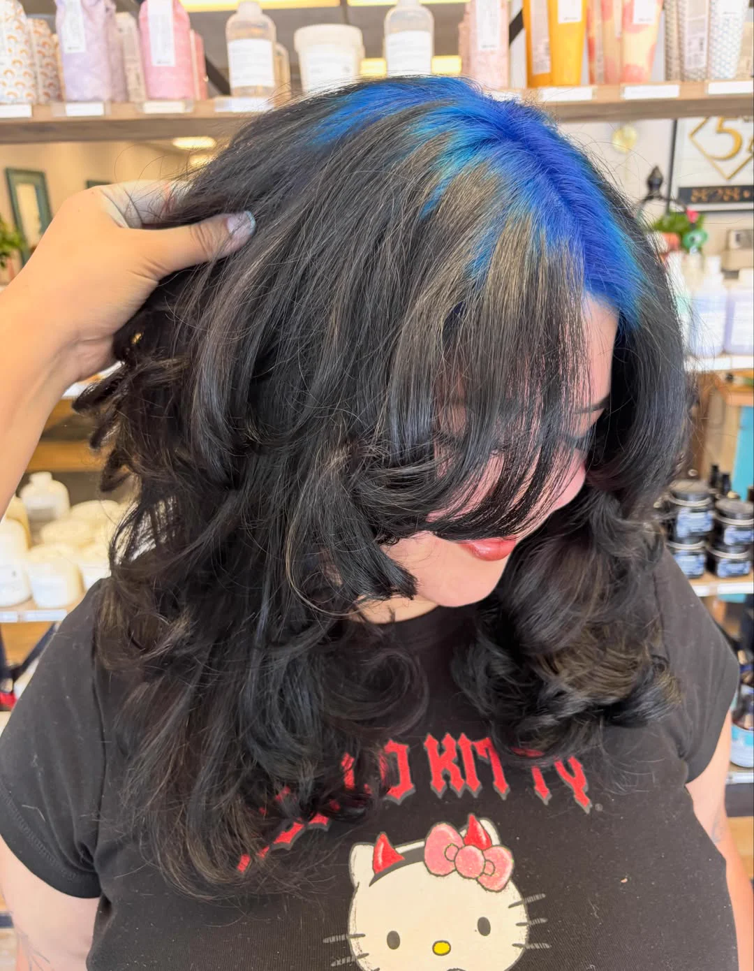 Top-front view of medium black waves with electric-blue roots sweeping asymmetrically from a side part.