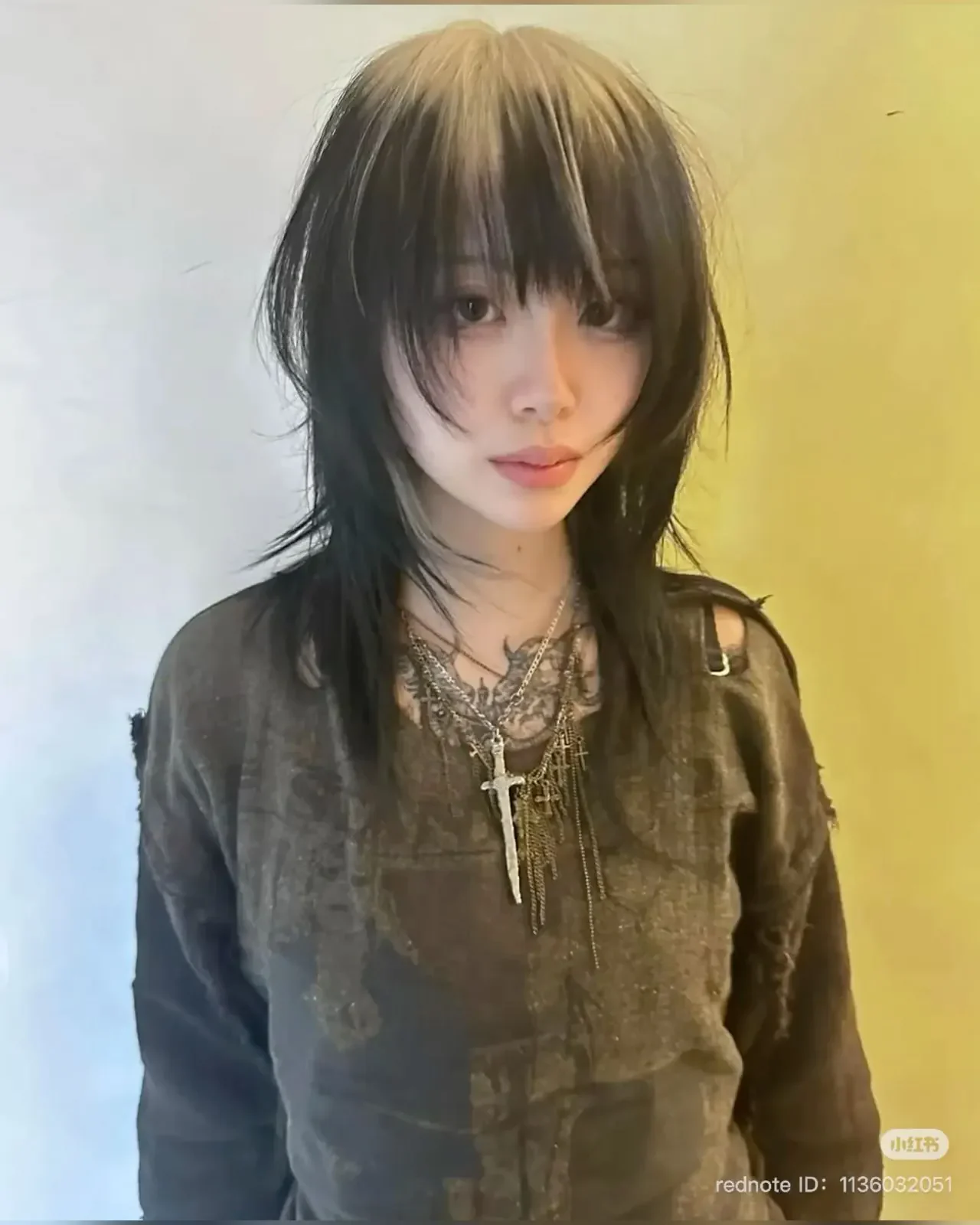 Black choppy wolf cut with soft brown ghost roots and long face-framing layers.