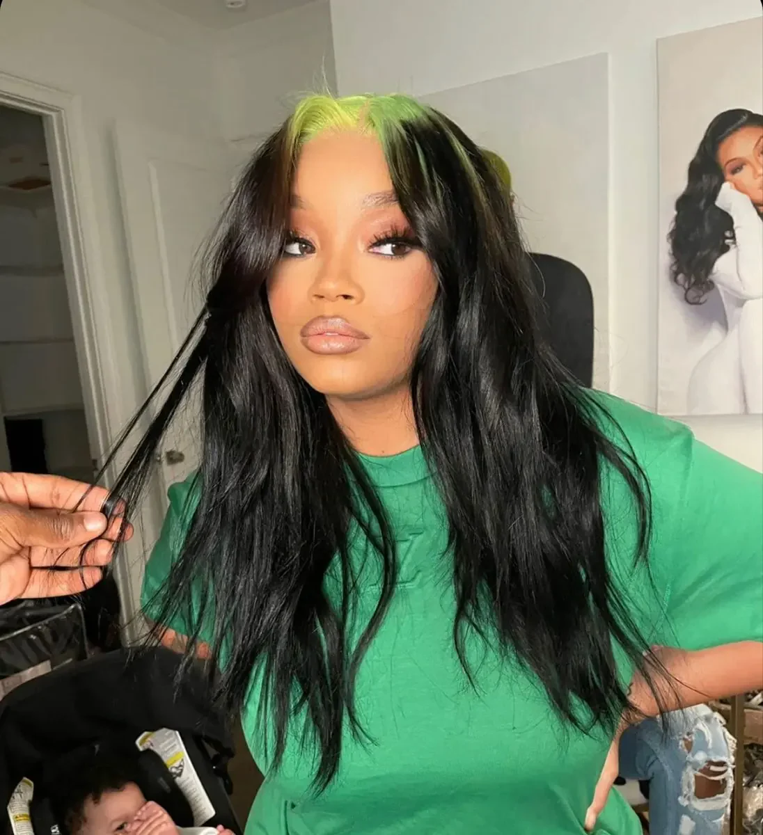 Woman with long black body-wave hair and a green peekaboo section near the front roots.