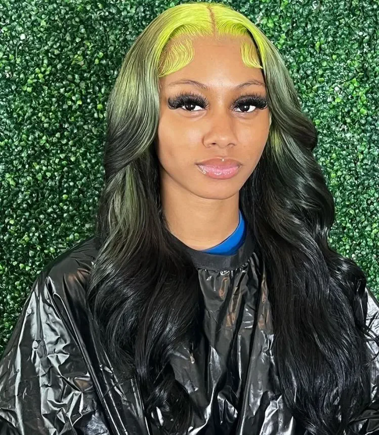 Woman with long black waves and chartreuse-green color beginning at the front roots and framing both sides of the face.