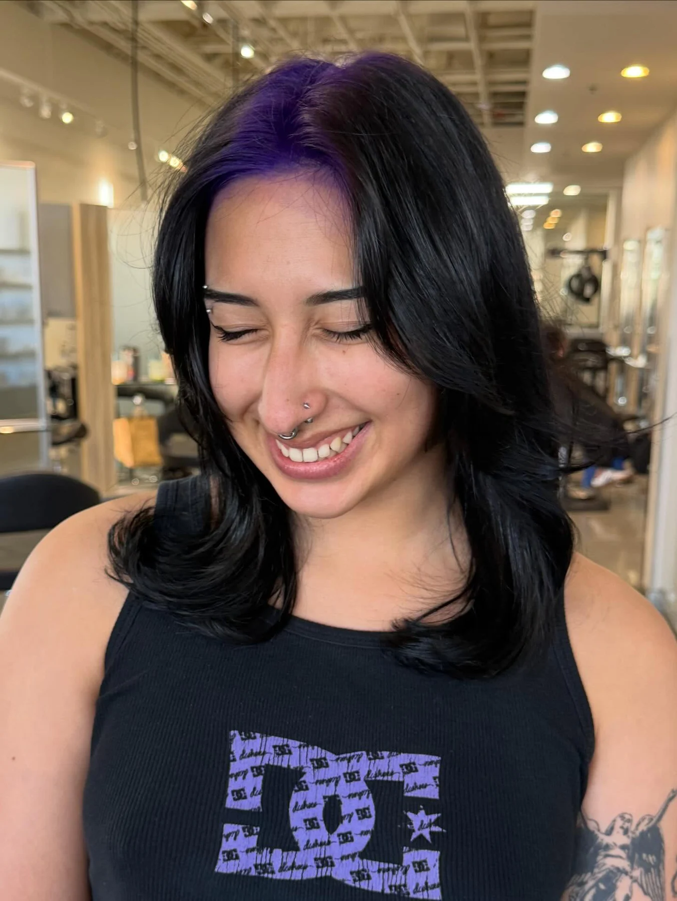 Woman with a medium black layered blowout and a narrow deep-violet section at the front part roots.