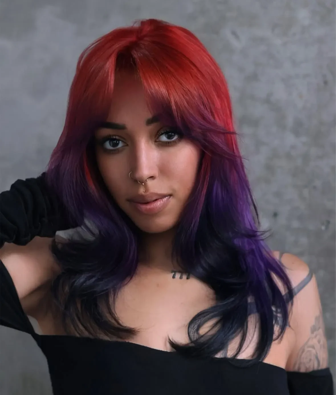 Front portrait with broad red roots transitioning through violet face-framing layers into long blue-black glam waves.