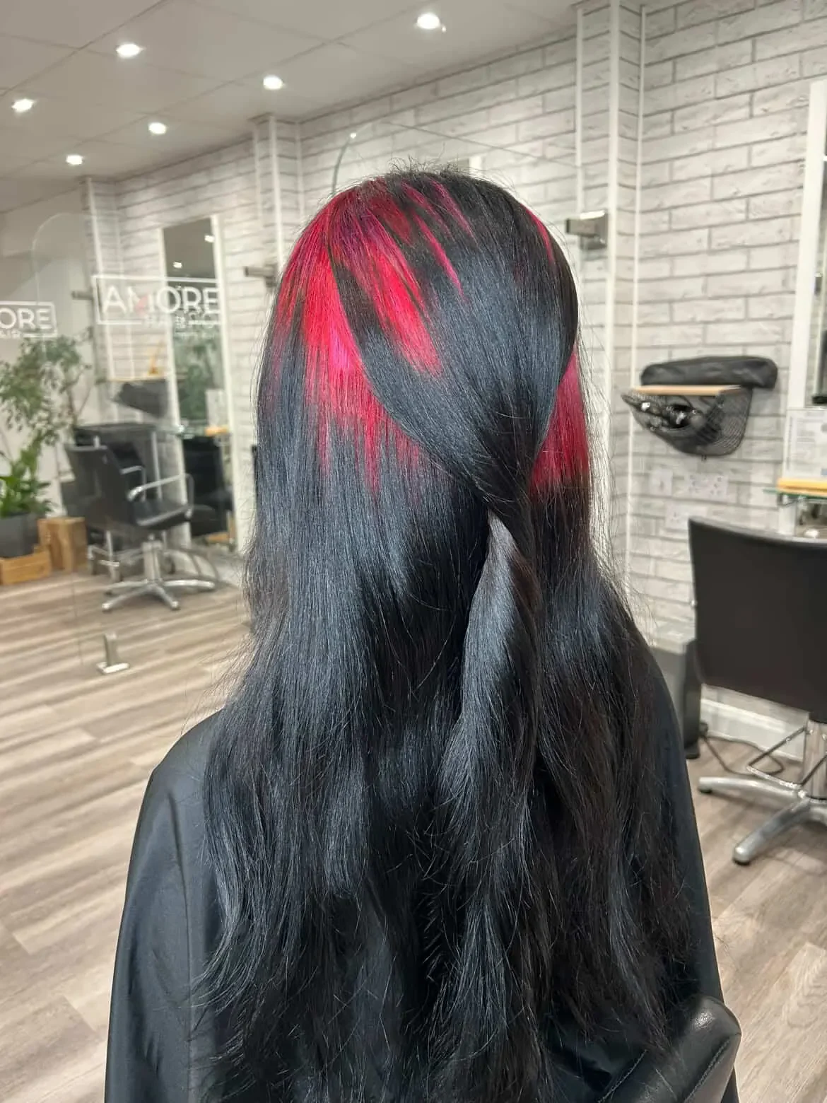 Back view of long soft black waves with a red top-root panel visible between sections.