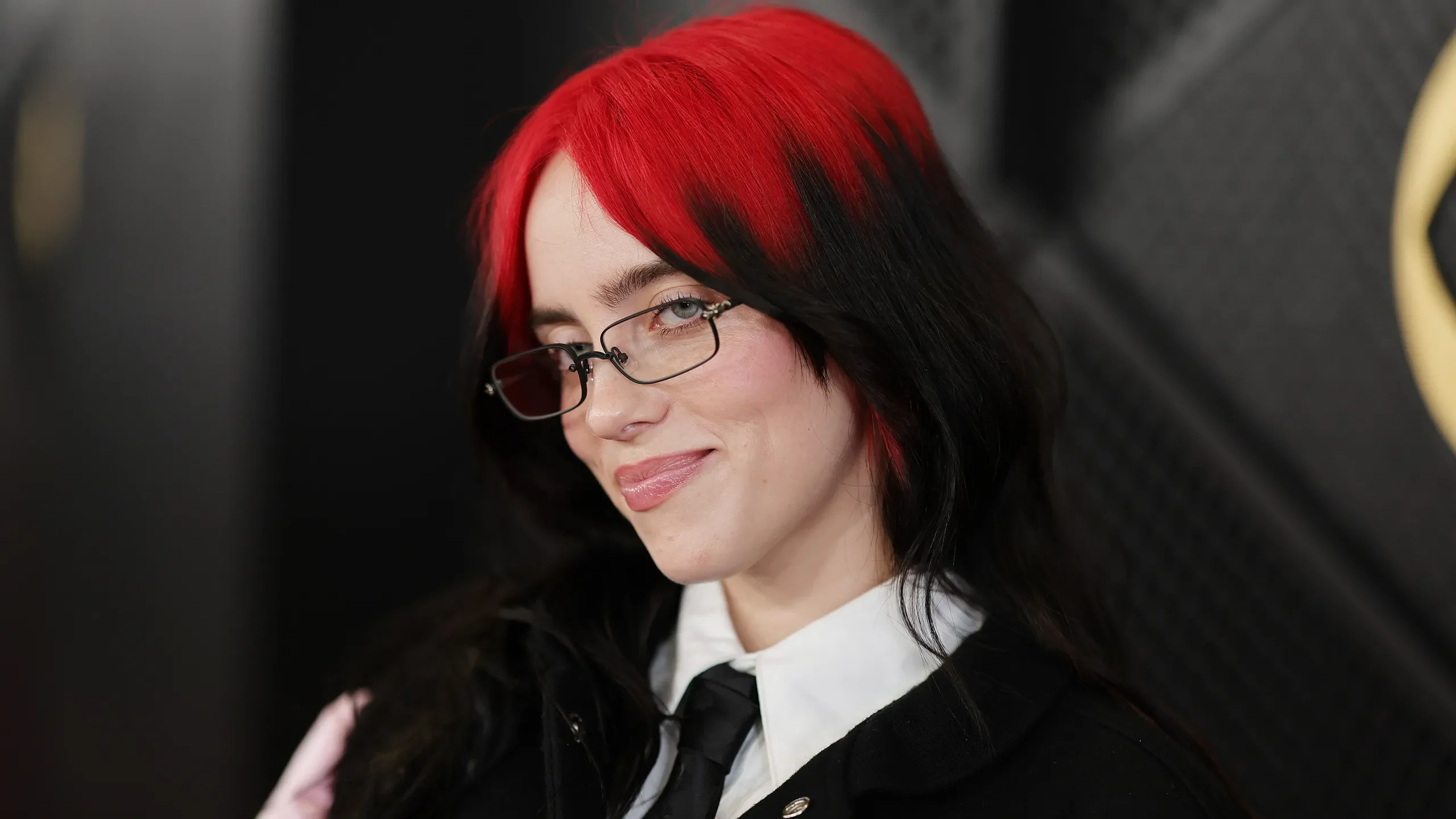 Woman with a short sleek black bob and true-red color at the split fringe roots.