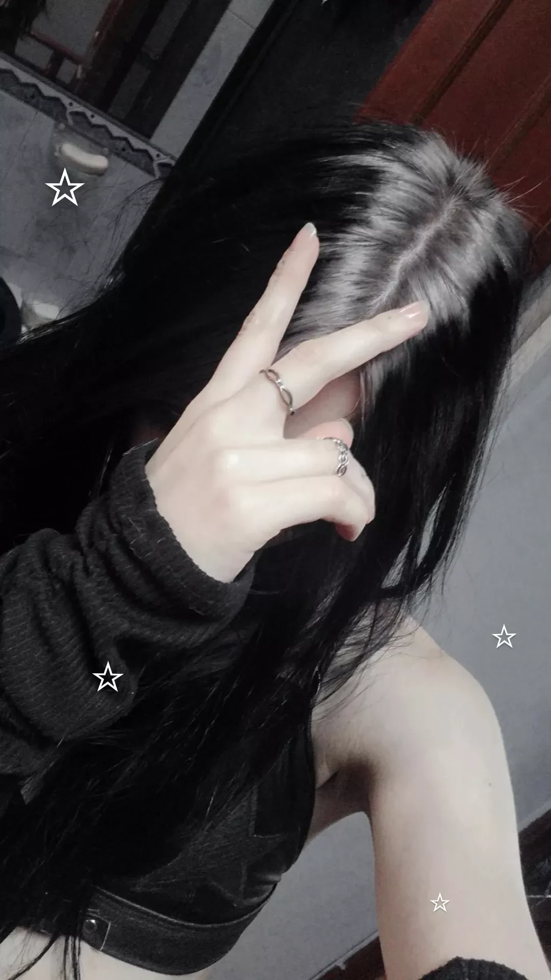 Woman with long loose black waves and a white stripe following the center roots.