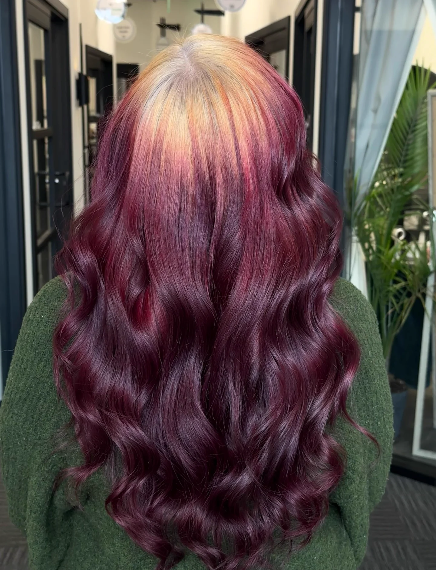 Back view of long burgundy-red waves with a broad pale-blonde crown root section and a softly blended edge.