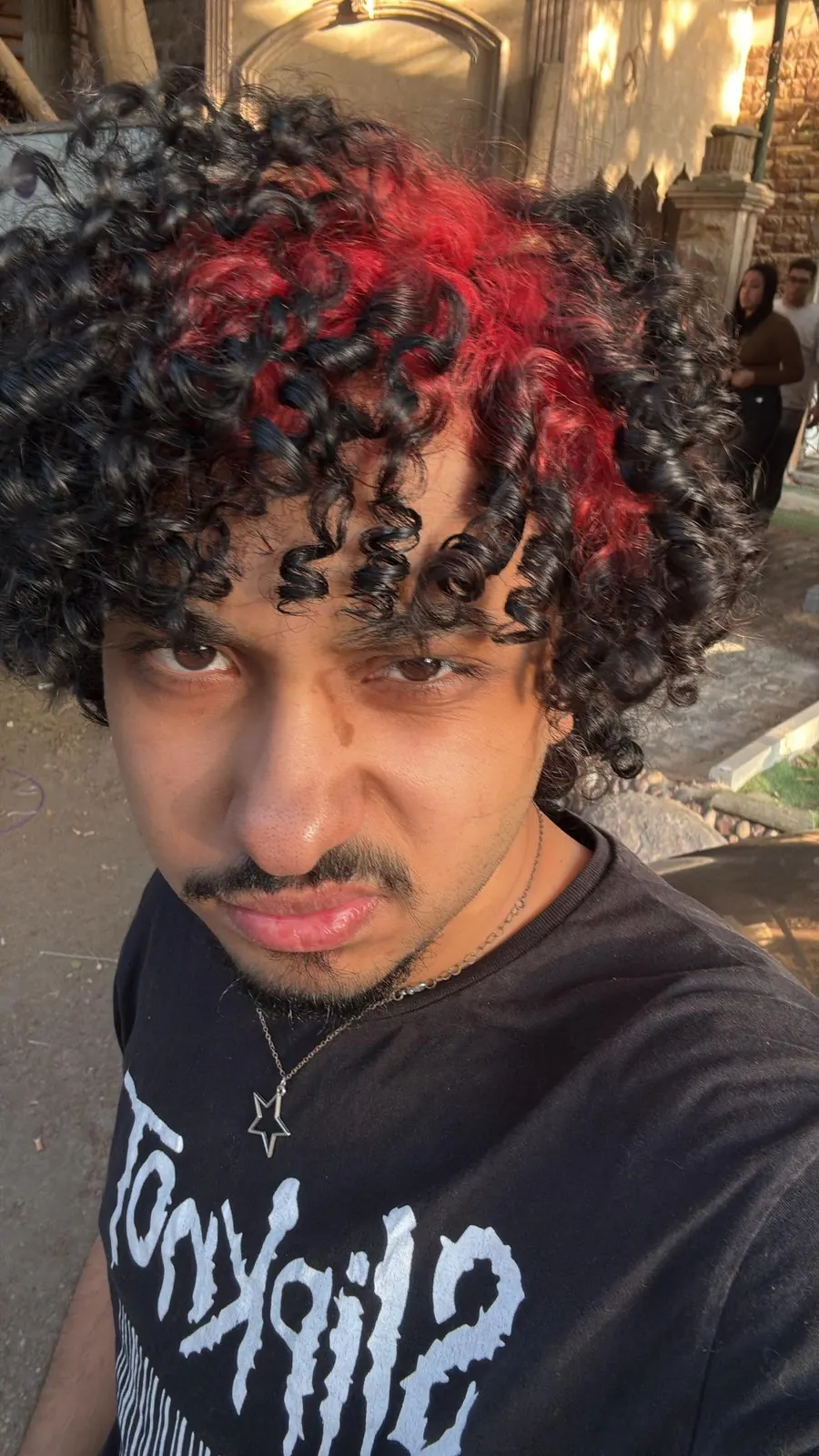 black men's medium curly cut with crimson red ghost roots.