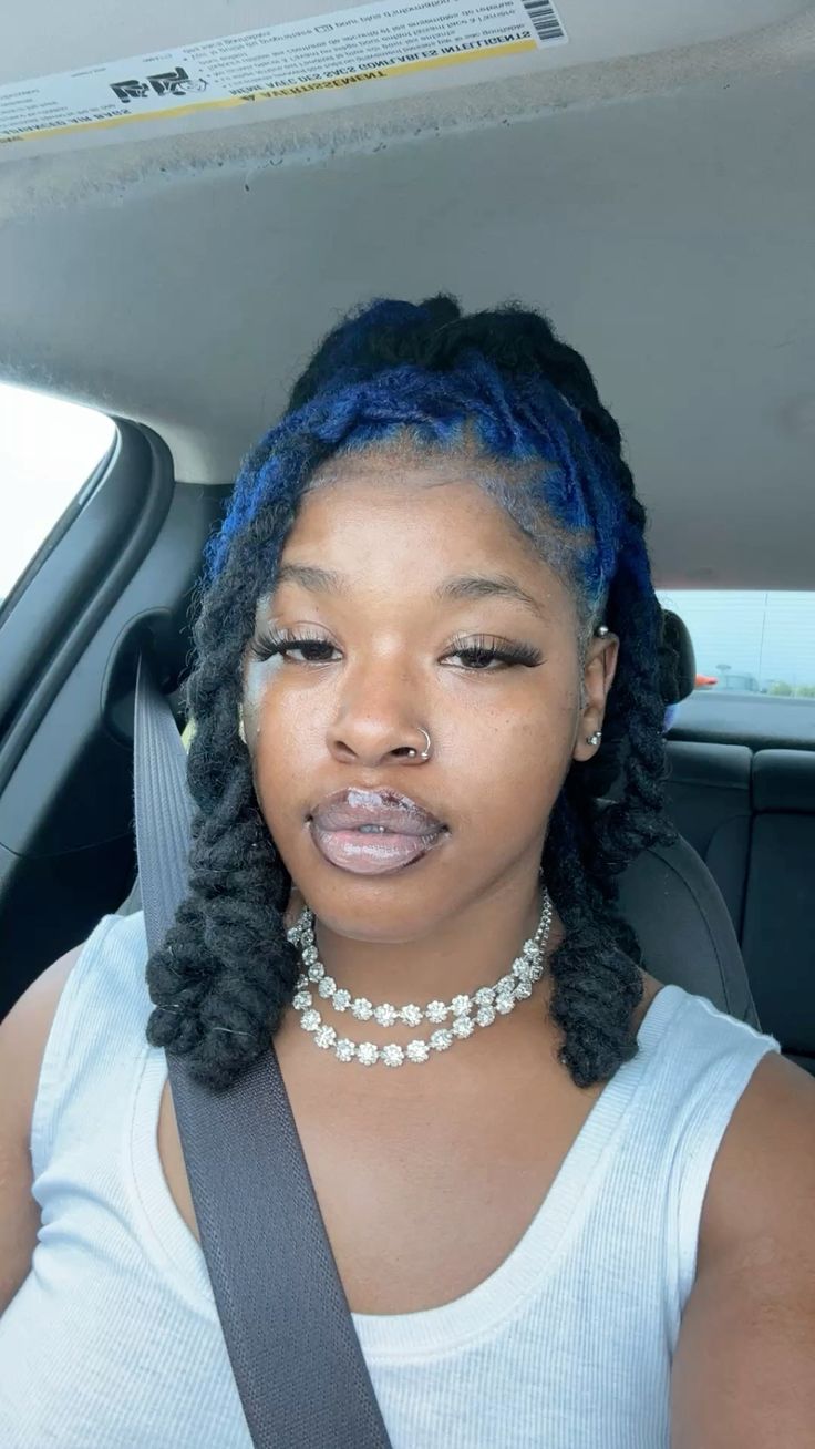 Medium black locs with cobalt blue ghost roots through the top crown panel.