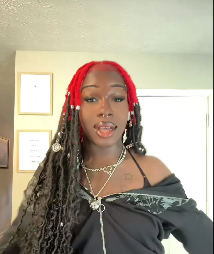 Woman with long black box braids and crimson-red color visible across the crown rows and braid roots.