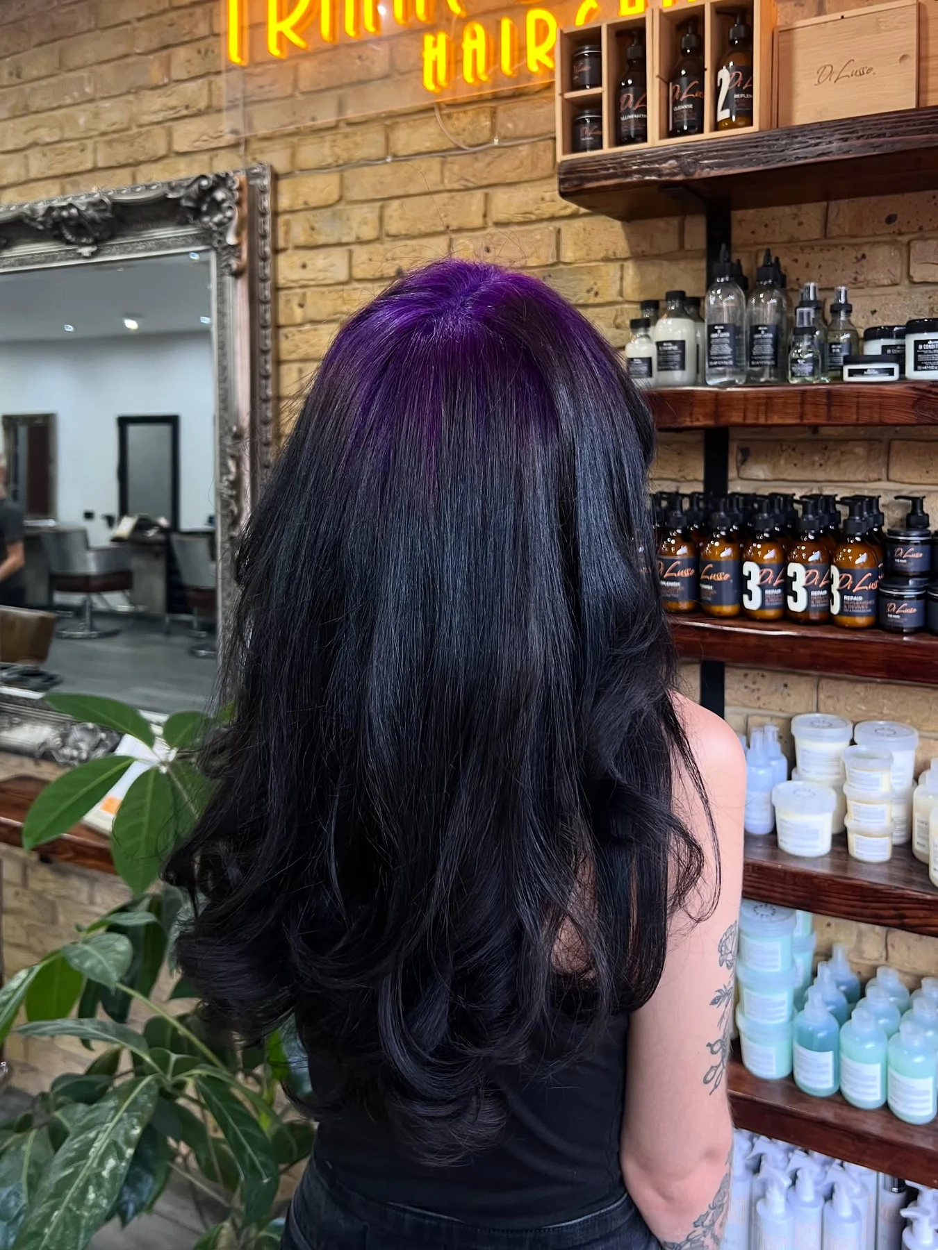Back view of long glossy black layered waves with a deep-violet crown panel.