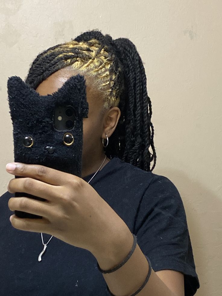 Long black locs with gold blonde ghost roots in a side-shaved panel.