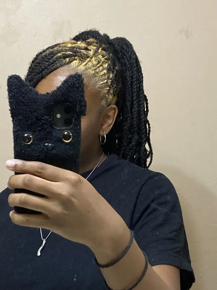 Long black locs with gold blonde ghost roots in a side-shaved panel.