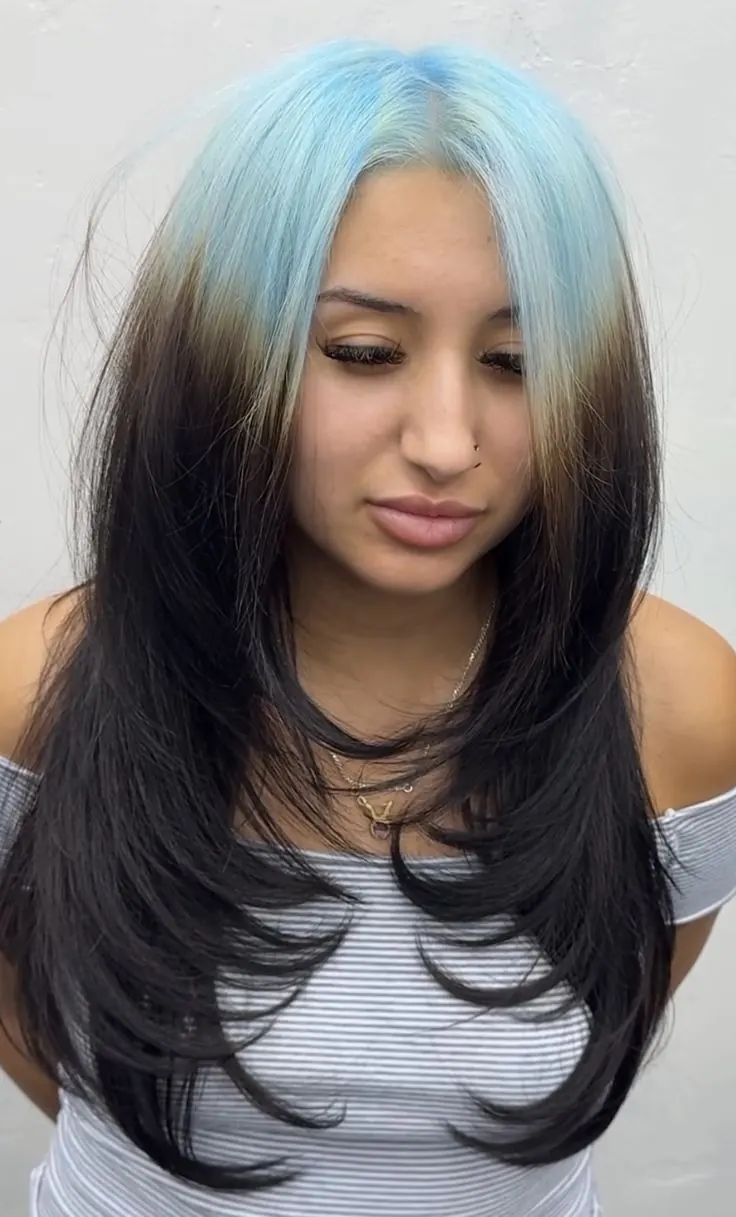 Long black layered straight hair with ice blue ghost roots framing the face.