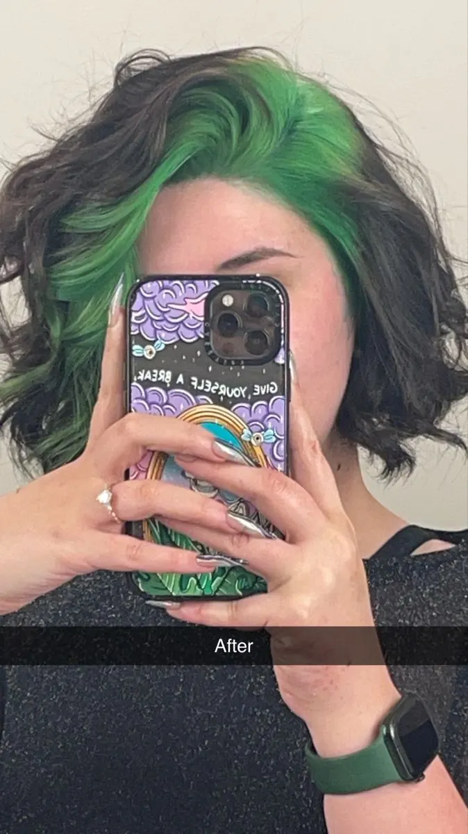 Short black wavy bob with neon green ghost roots through the top panel.