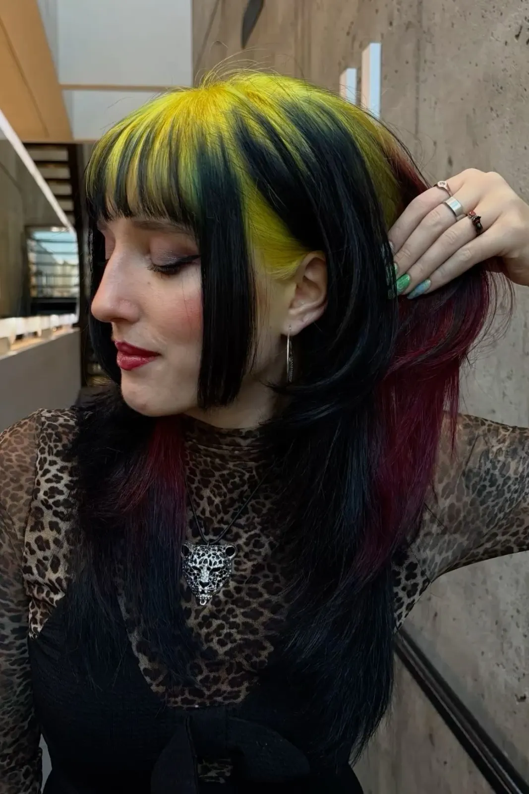 Side profile of long straight black hair with wide neon-yellow root panels across the top and fringe area.