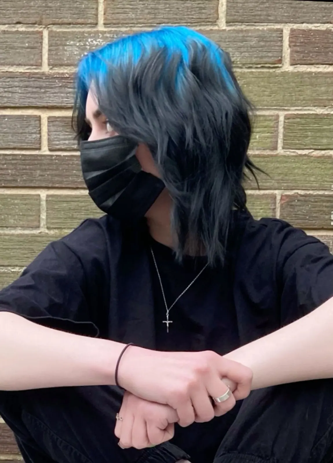Black hair with electric blue ghost roots, long straight split fringe, front portrait.