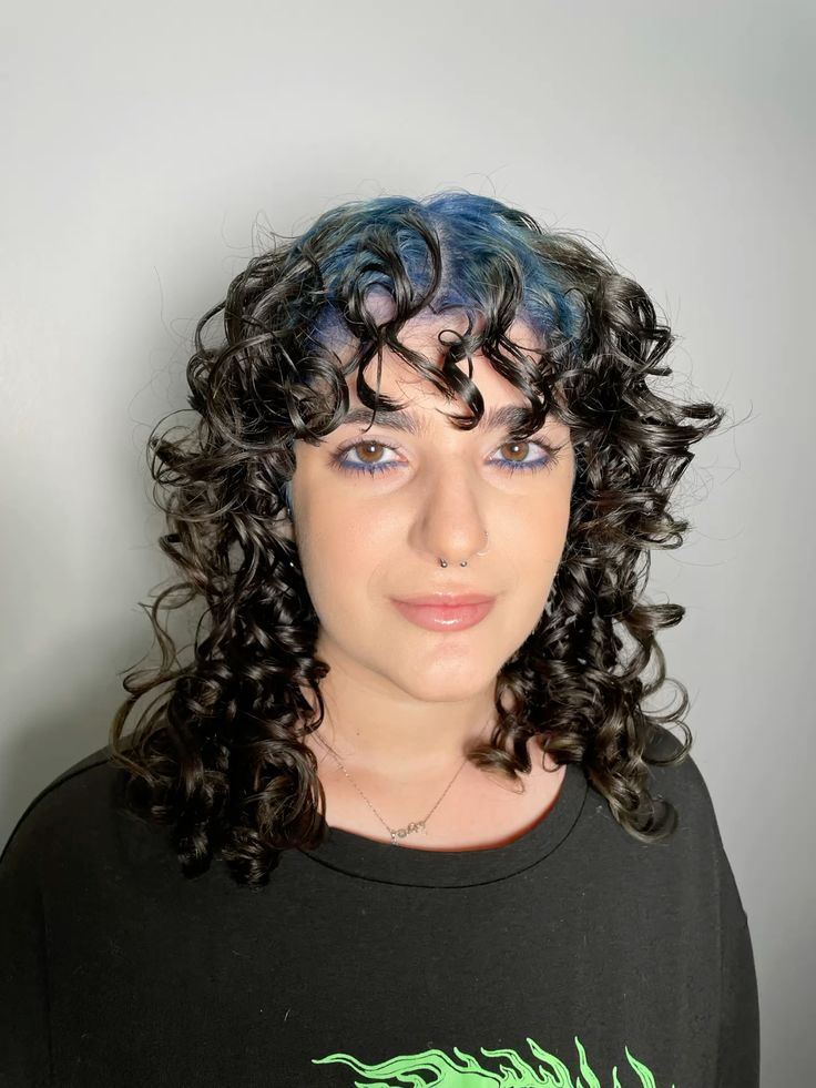 Curly shag with curtain bangs and silver-blue ghost roots through the fringe and top.
