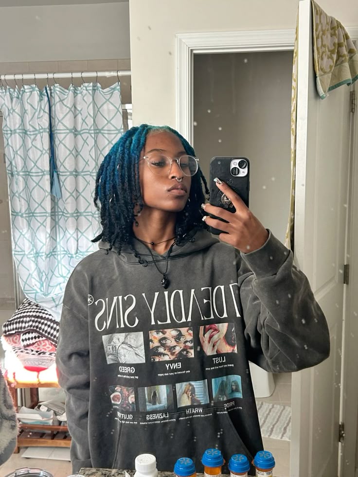 Medium black locs with teal blue ghost roots through a crown panel.