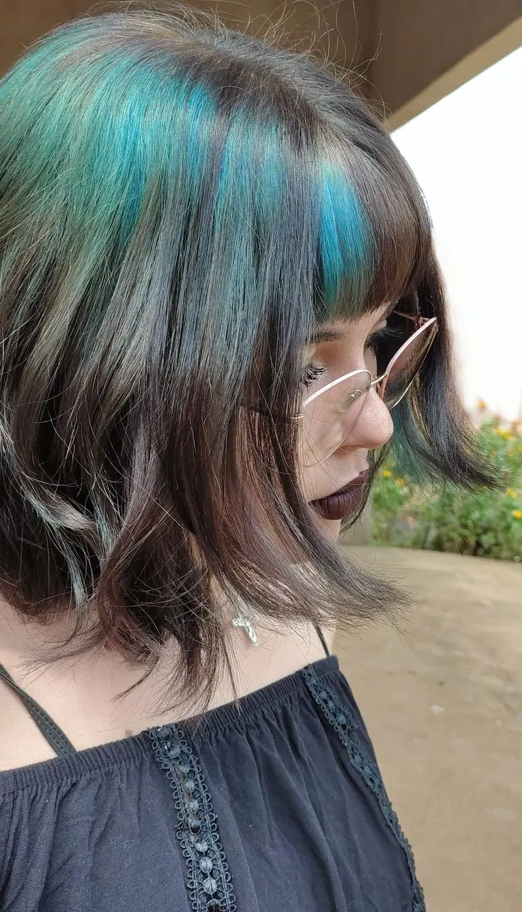 Short black textured bob with teal-blue ghost roots through the top layer.