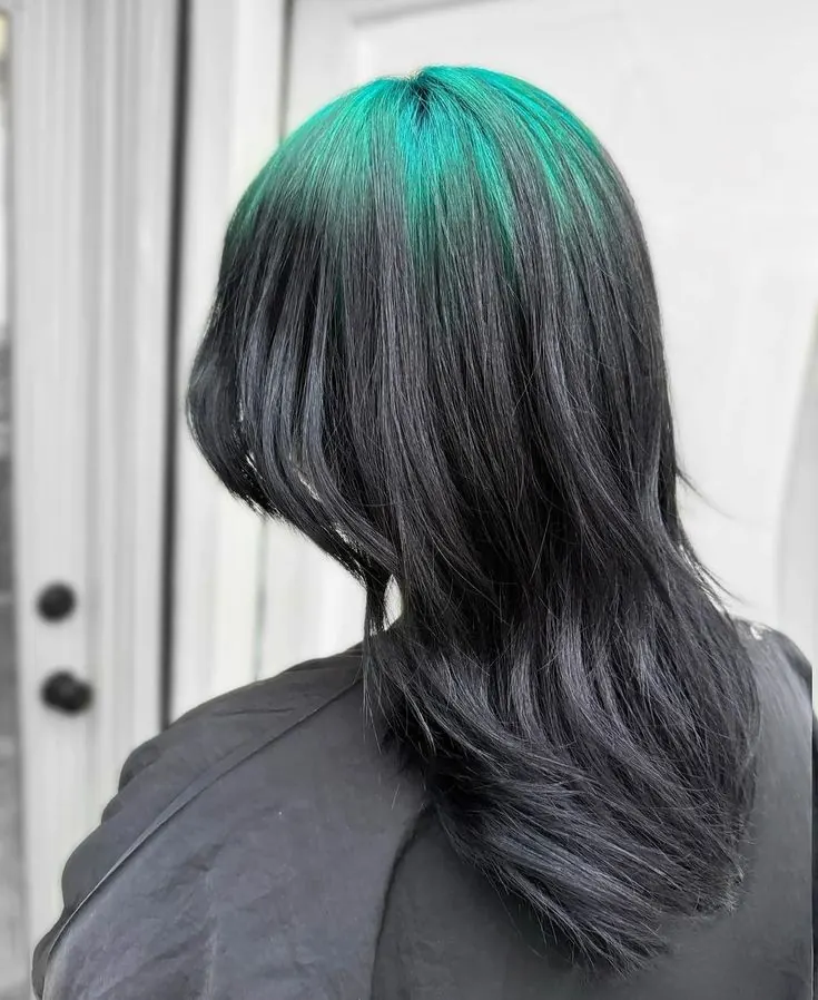 Medium-long black layered lob with teal ghost roots concentrated through the crown.