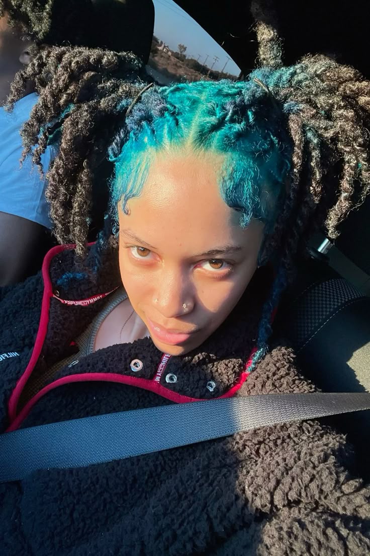 Medium curly black locs with turquoise blue ghost roots through the top panel.