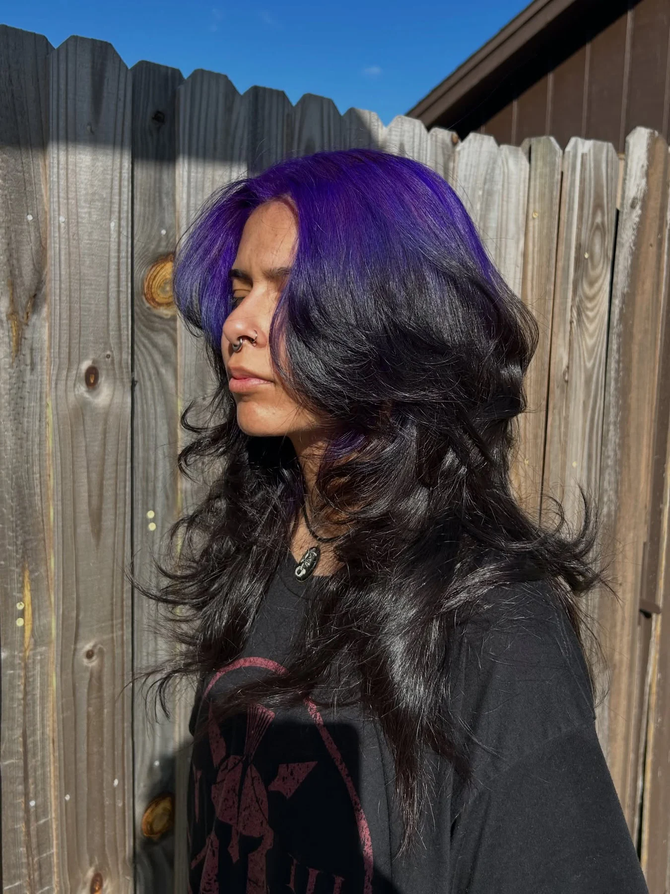 Woman with long black layered waves and a broad vivid-violet panel across the front and crown.