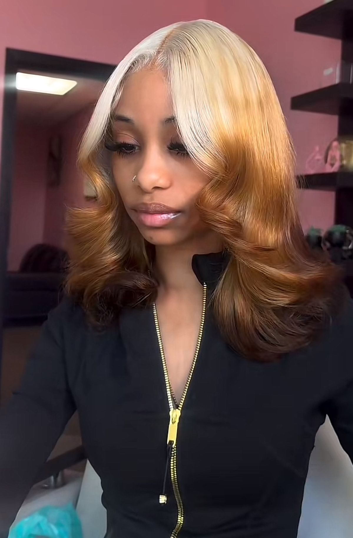 Caramel shoulder-length curls with platinum blonde ghost roots and a soft center part.