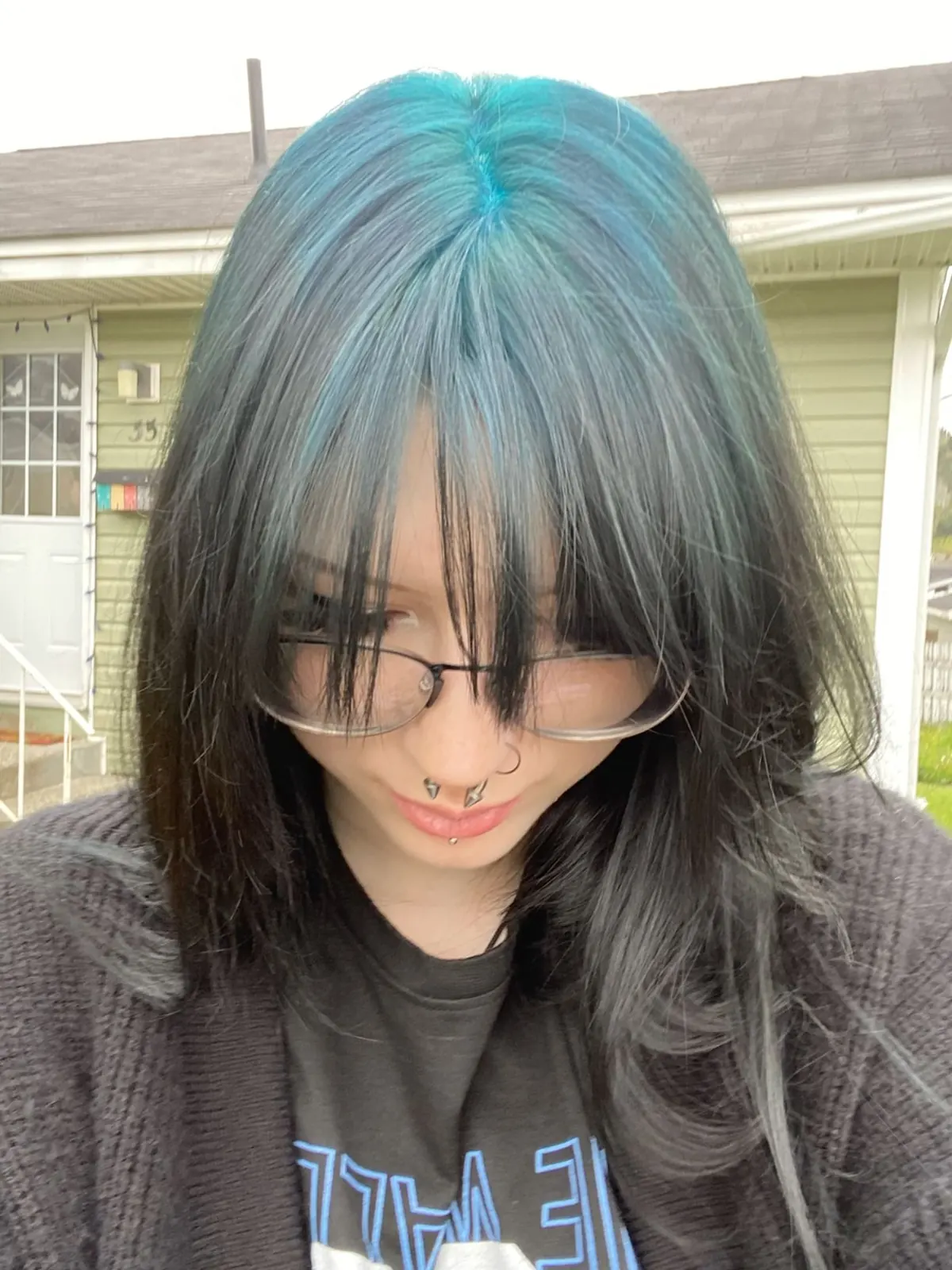 Medium brown straight hair with teal-blue ghost roots through the crown panel.