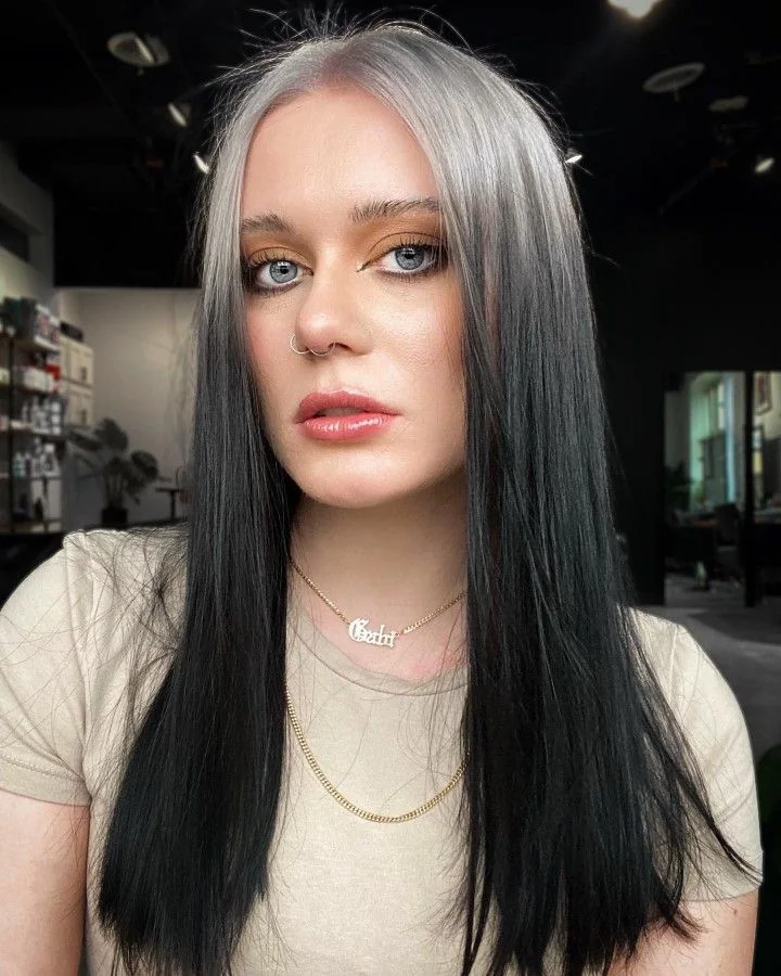 Long sleek black hair with silver-white ghost roots through the center part.