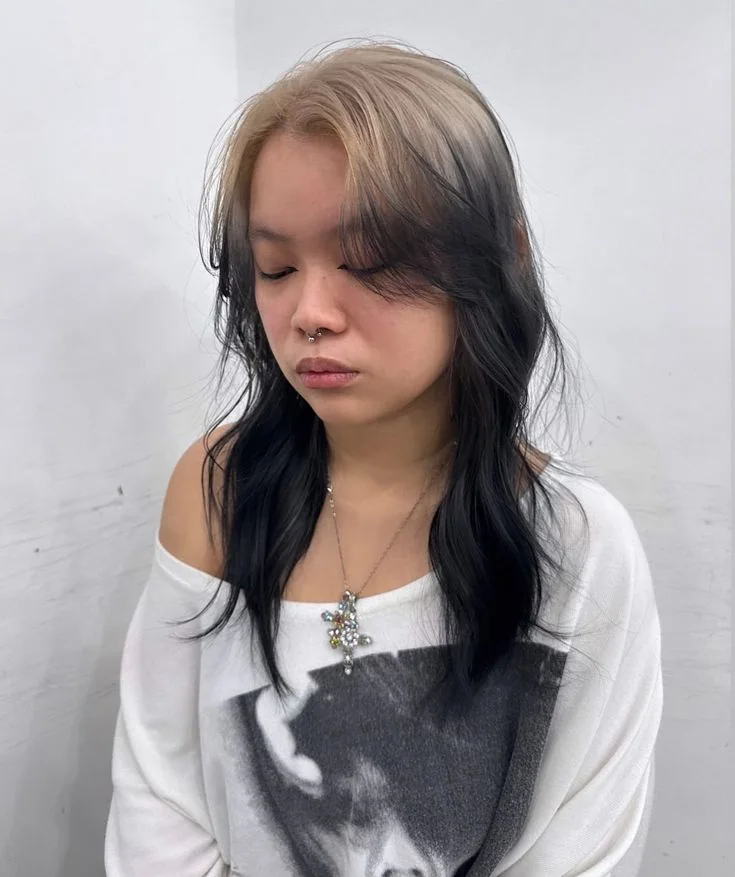 Medium black wolf cut with smoky silver ghost roots through the center part and curtain bangs.